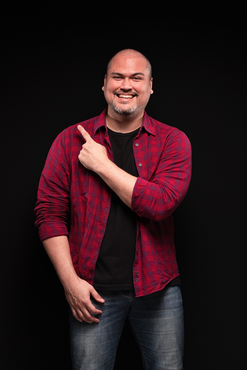 A smiling man pointing to the left.